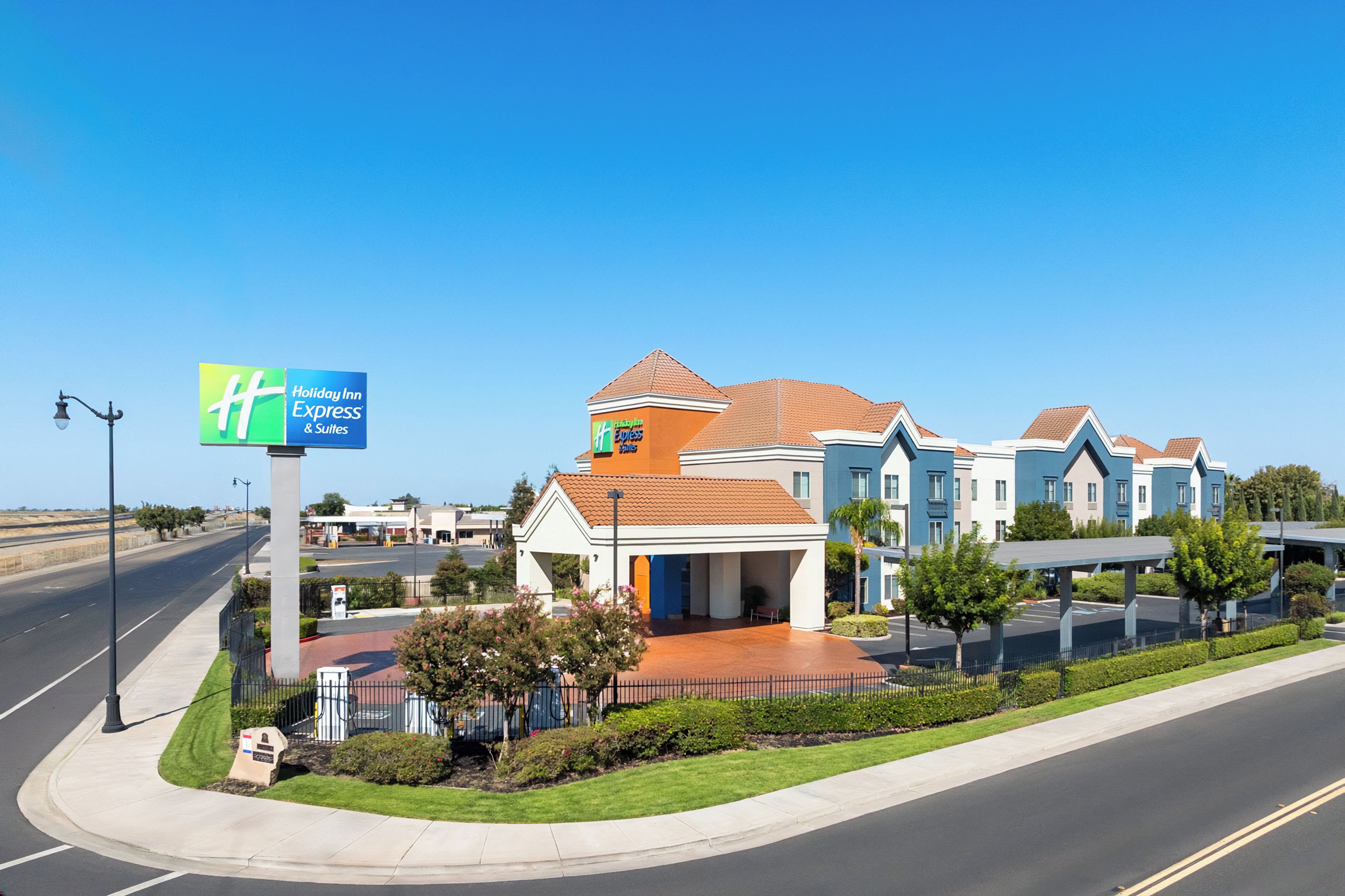 A Holiday Inn Express & Suites with a modern design, featuring a central building with a red-tiled roof and a smaller attached structure with a blue facade.