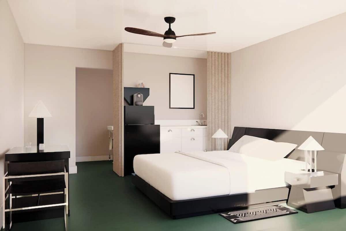 Una habitación de hotel moderna con una cama, mesitas de noche, ventilador de techo y vistas al exterior.