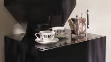 A black coffee machine with cups labeled 'PERR' on a black table.
