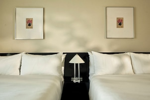 Une chambre d’hôtel avec deux lits, une table de chevet avec une lampe et deux tableaux encadrés au mur.