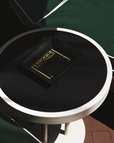 A round table with a black surface and a black box labeled 'PEROQUET' on it.