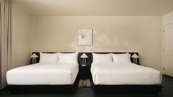 A hotel room with two beds, a nightstand, a lamp, and a framed picture on the wall.