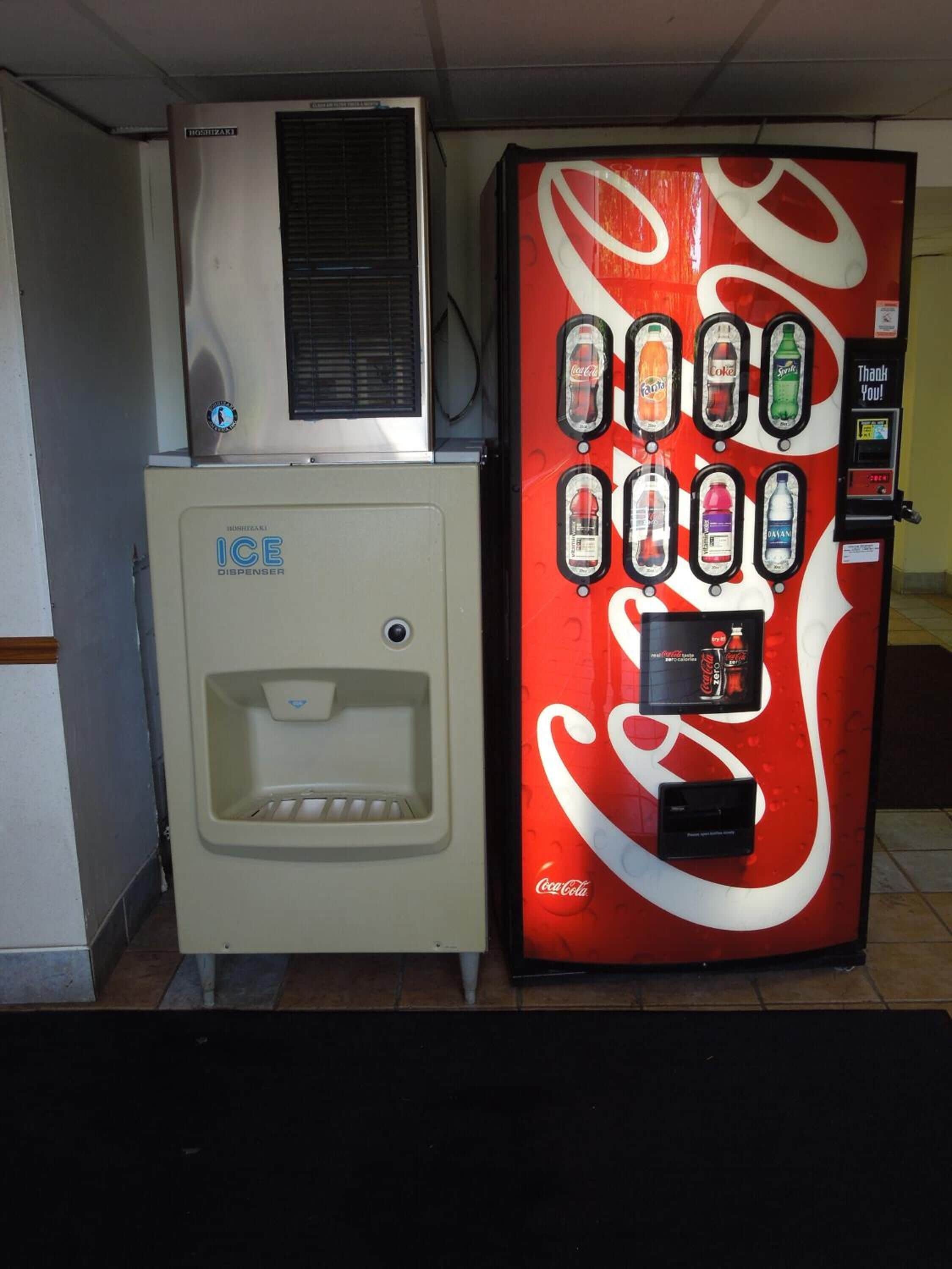 A vending machine with a Coca-Cola logo and a smaller ice dispenser unit beside it.