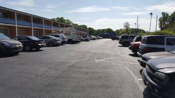 Een parkeerplaats met meerdere auto's en een gebouw met een blauw balkon op de achtergrond.