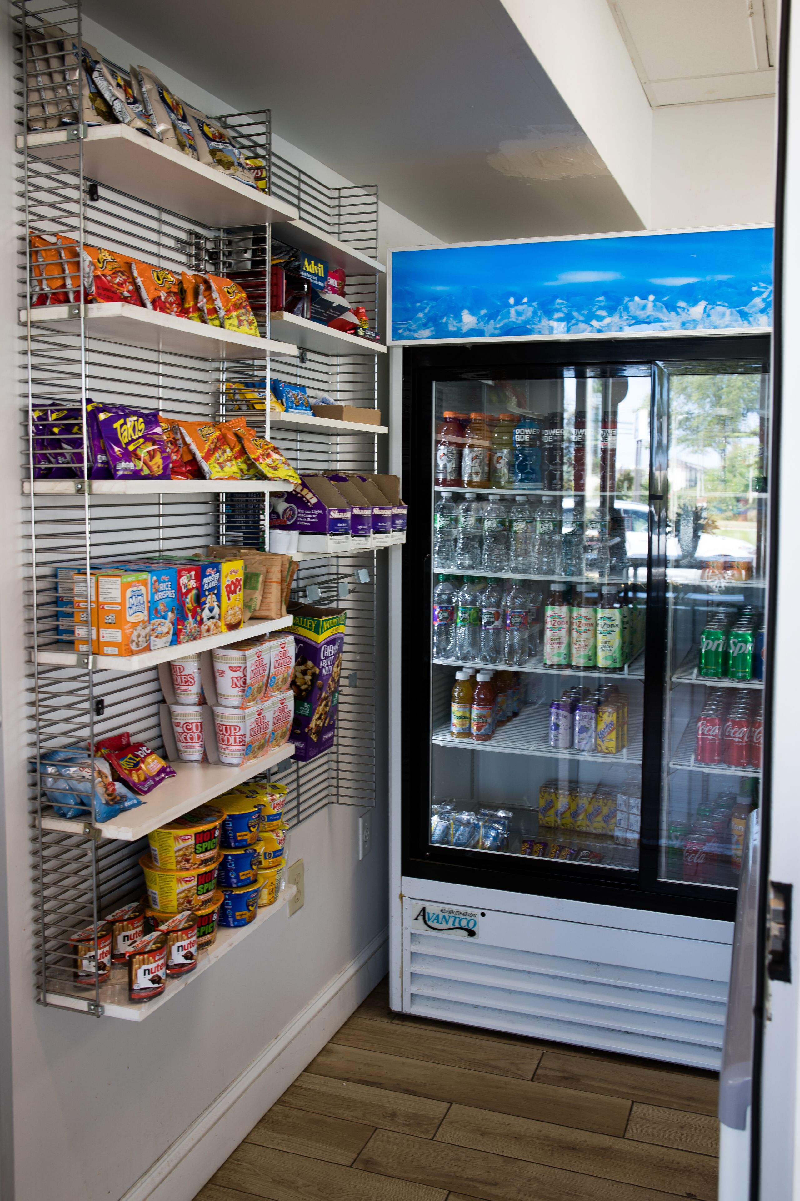 Een automaat gevuld met snacks en drankjes, en planken met diverse etenswaren.