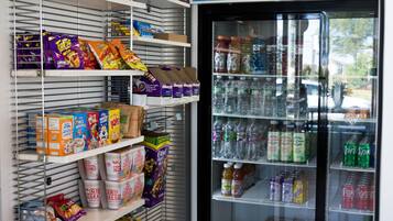 A vending machine stocked with snacks and drinks, and shelves with various food items.
