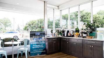 A modern kitchen with dark cabinets, a coffee machine, and a large window offering a view of the outdoors.