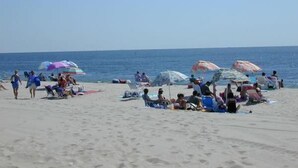 Una playa con gente tomando el sol y caminando.