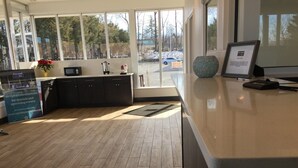 Un moderno vestíbulo de hotel con piso de madera, una recepción, una máquina de café y un amplio ventanal con vista al exterior.