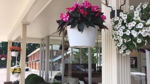 Un edificio con un acceso cubierto, plantas en macetas y una pared de ladrillo.