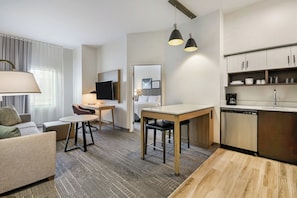 A modern hotel room with a living area, dining table, and kitchenette. - Staybridge Suites Toledo - Maumee by IHG (Maumee)