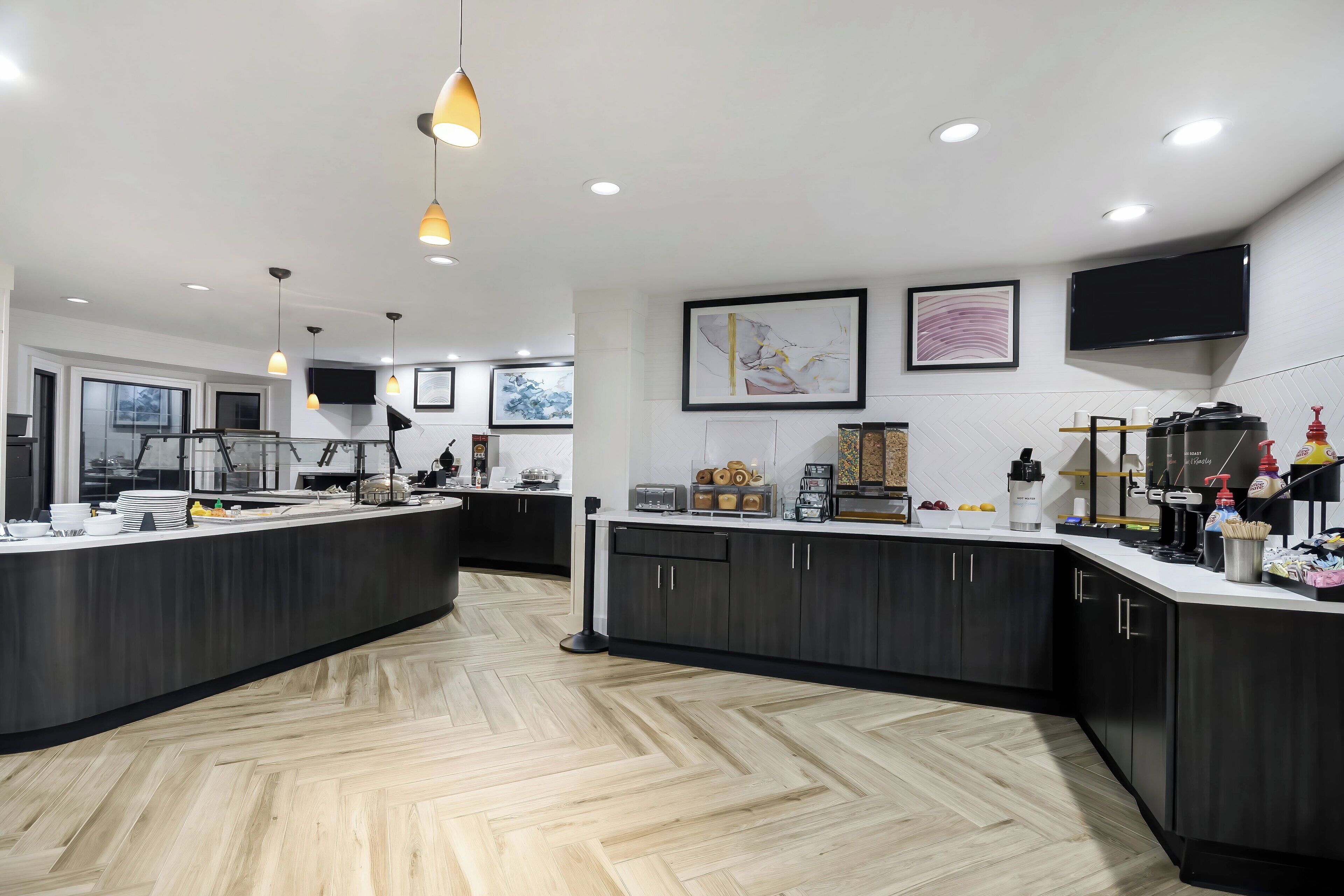 Una cocina moderna con una isla central, armarios negros y un suelo de madera en espiga.