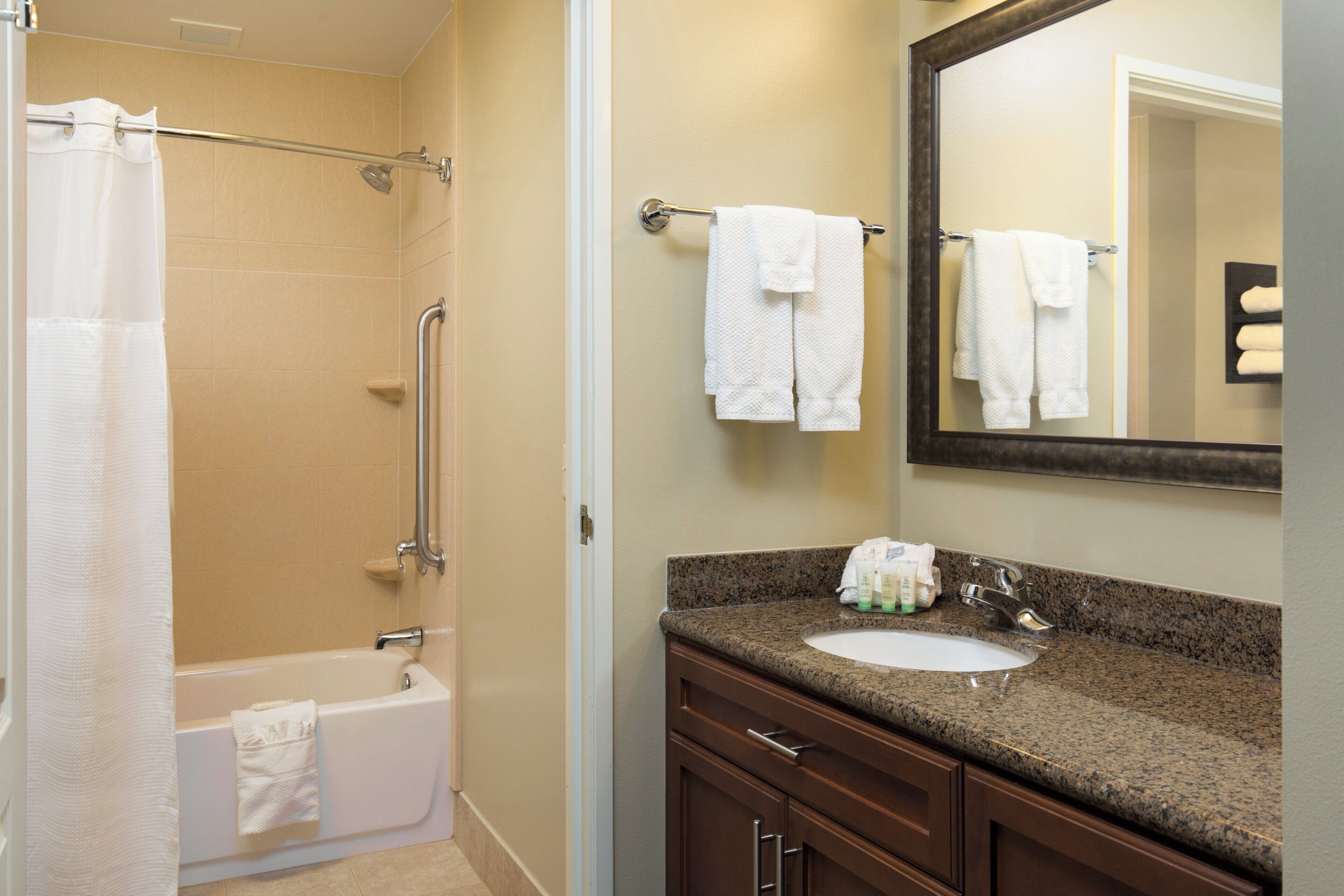 A bathroom with a bathtub, a sink, a mirror, and a towel rack.