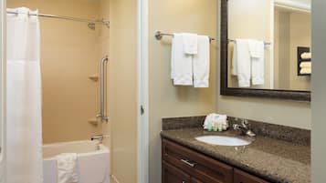 A bathroom with a bathtub, a sink, a mirror, and a towel rack.