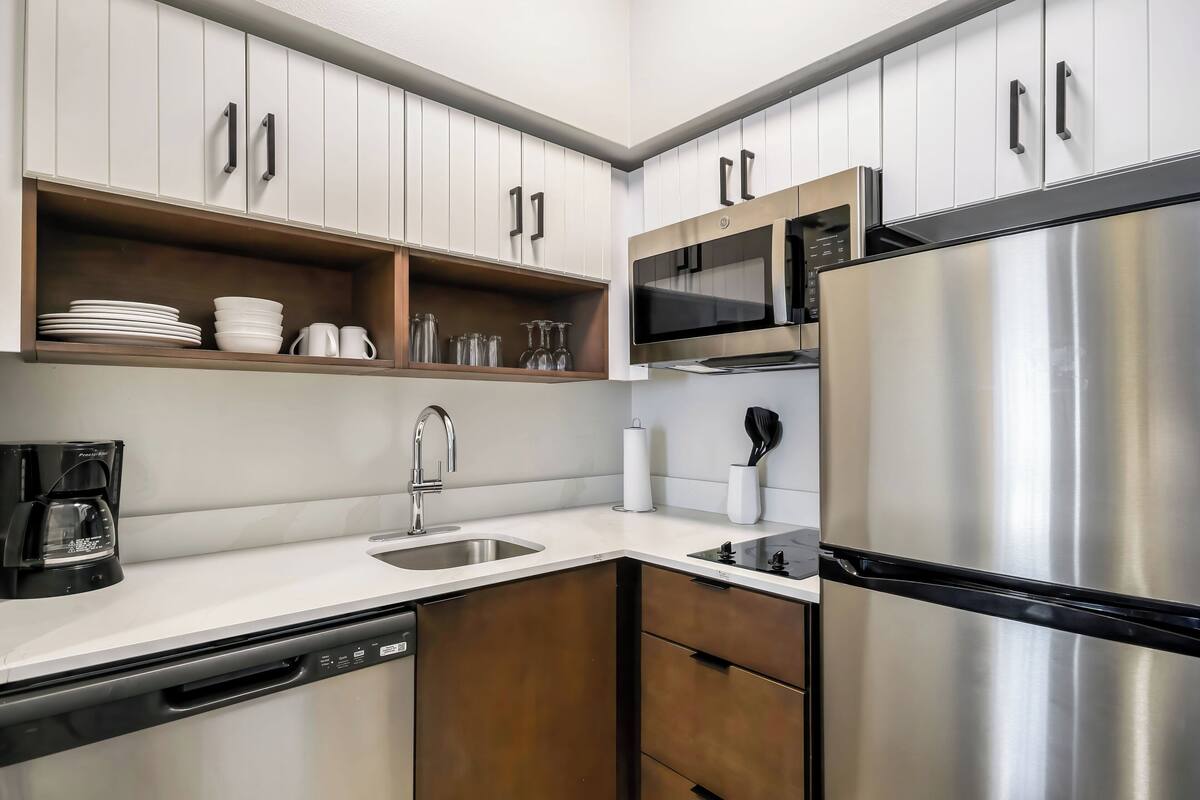 A modern kitchen with white cabinets, stainless steel appliances, and a dishwasher.