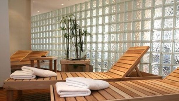 A spa room with wooden loungers, a small table, and a bamboo plant.