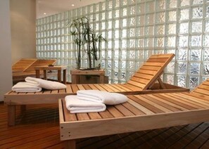 A spa room with wooden loungers, a small table, and a bamboo plant. - Fueguino Hotel (Ushuaia)