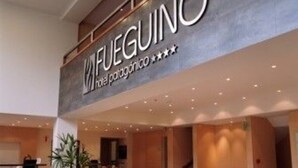 A hotel reception area with a modern design, including a reception desk and a staircase leading to upper floors.