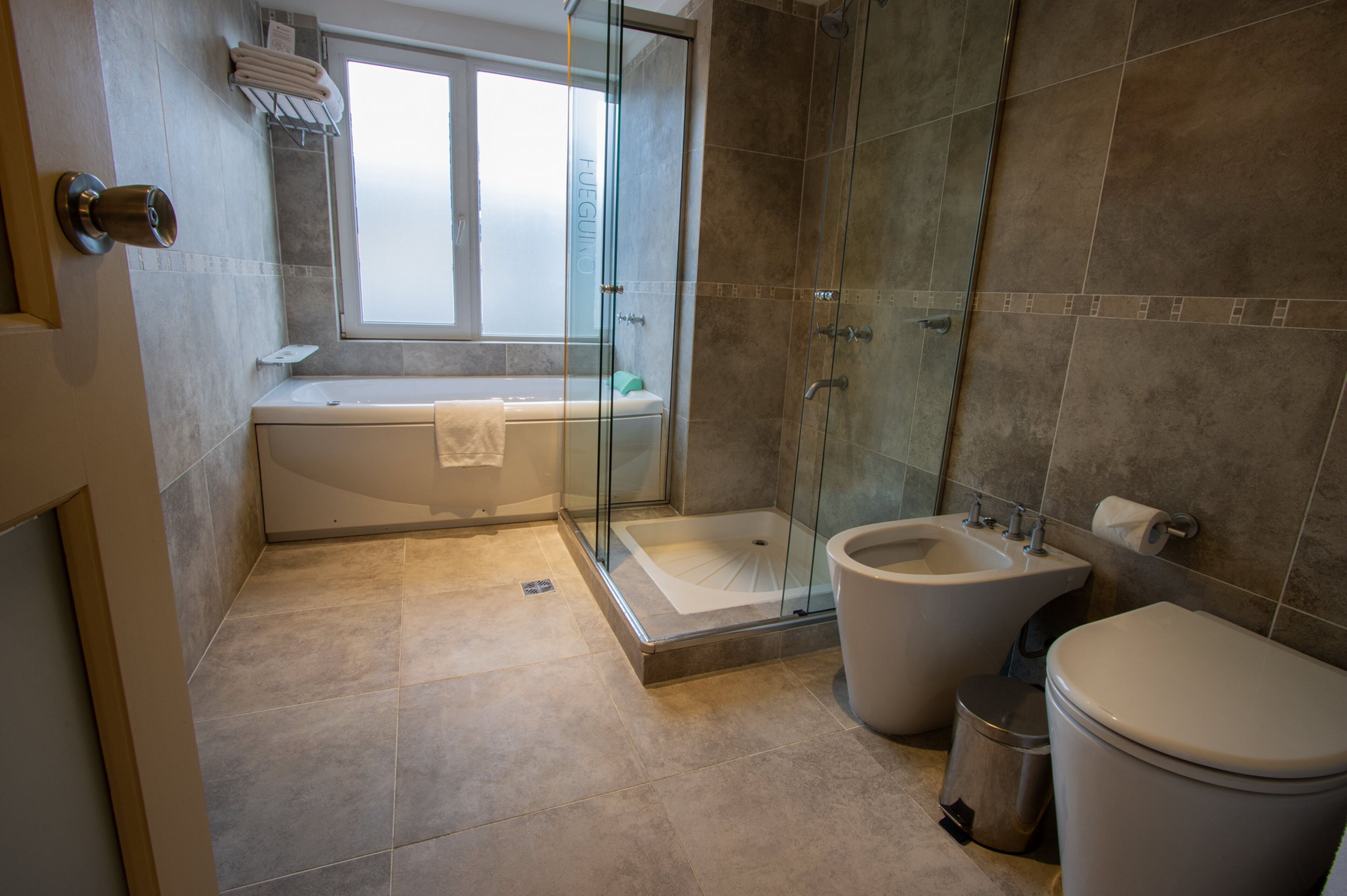 Un bany modern amb dutxa de vidre, una banyera, un vàter i un lavabo.