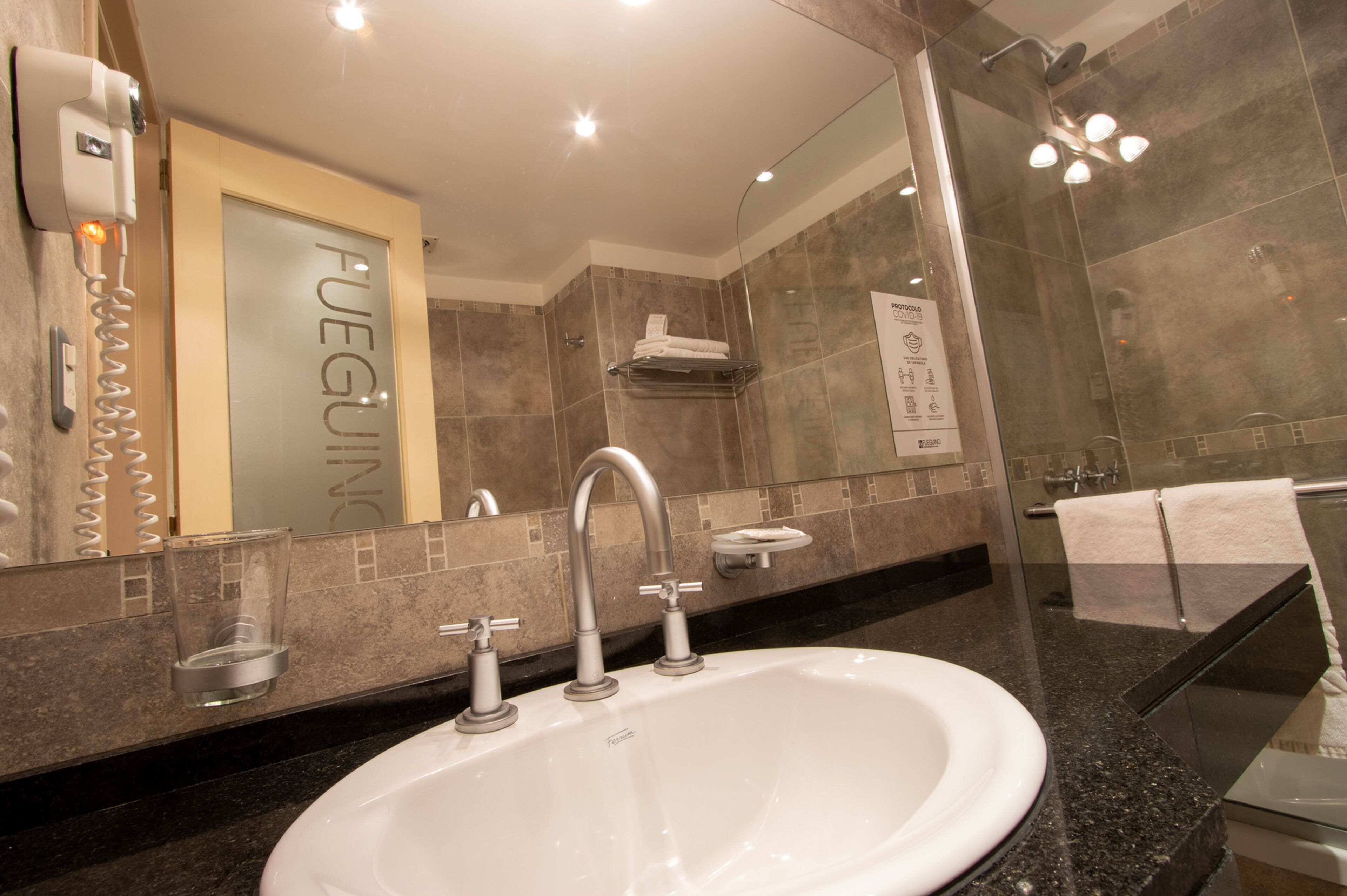 A modern bathroom with a large sink, a glass shower enclosure, and a towel rack.