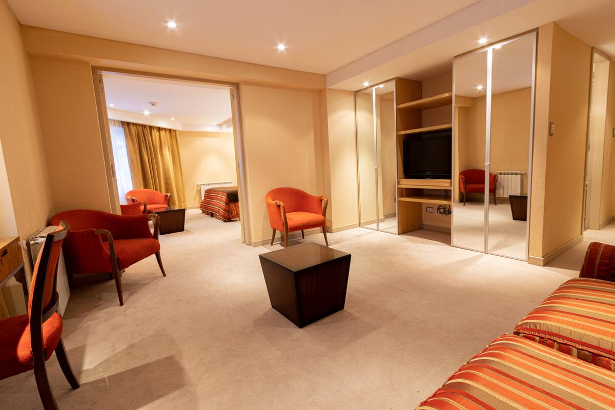 Ein Hotelzimmer mit einem großen Spiegel, einem Fernseher und zwei roten Sesseln.