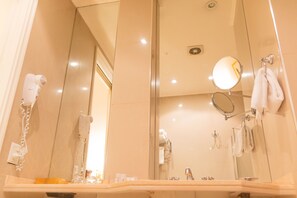 Un baño con un espejo grande, un secador de pelo y un perchero para toallas.