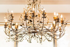 Un candelabro con múltiples brazos y bombillas, con detalles decorativos de hojas y ramas.