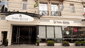 The exterior of the Park Silver hotel with a large entrance, glass windows, and a Starbucks sign visible through the glass. - Park Silver Obelisco Hotel (Buenos Aires)