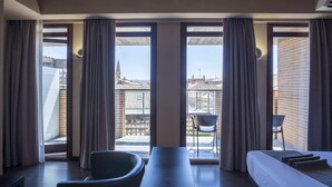 Een moderne hotelkamer met een ruim balkon, een bank, een eettafel en een stoel.