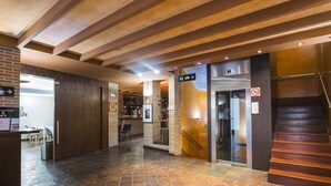 Een hotel lobby met een vloer van stenen tegels, een receptiebalie, een bar en een trap.
