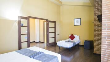 Una habitación de hotel con una cama, una mesita de noche pequeña, una silla y una puerta que da a otra estancia.