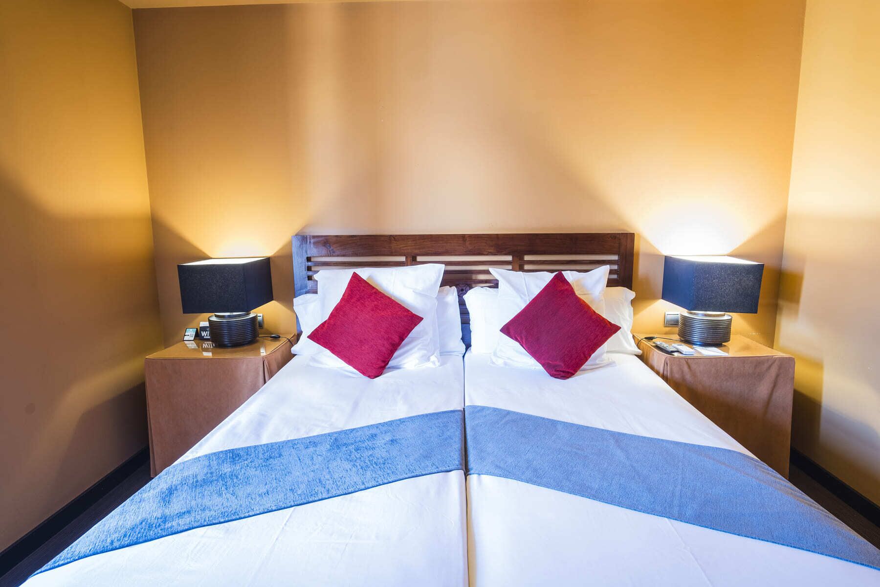 Una habitación de hotel con una cama grande, dos mesitas de noche y dos lámparas.