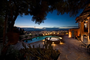 A pool area with a hot tub, surrounded by cacti and a stone patio.