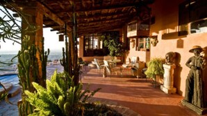 A covered outdoor area with a patio, seating, and decorative statues. - Casa Cordelli (San Miguel de Allende)