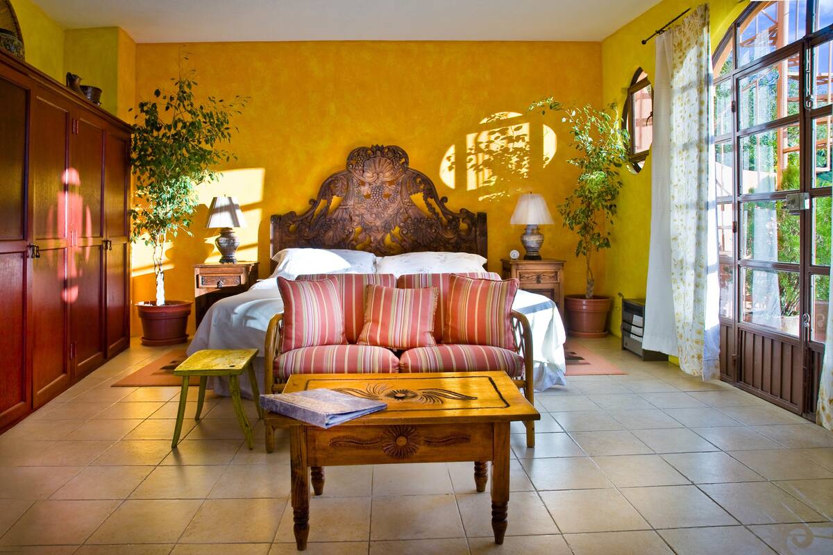 Une chambre à coucher avec un grand lit, une tête de lit en bois, un canapé et une petite table.