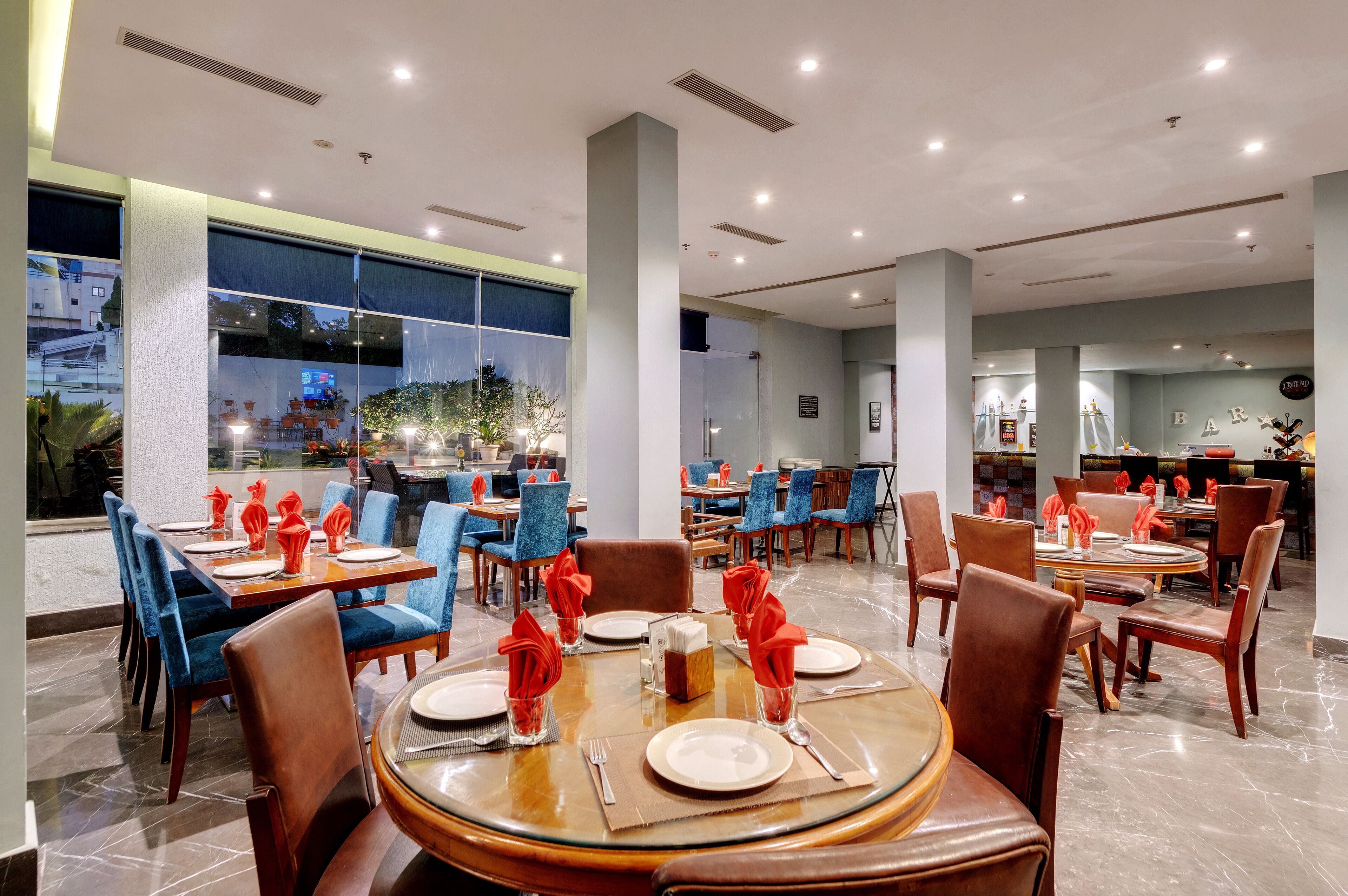 Un ristorante con tavoli rotondi, sedie blu e tovaglioli rossi.