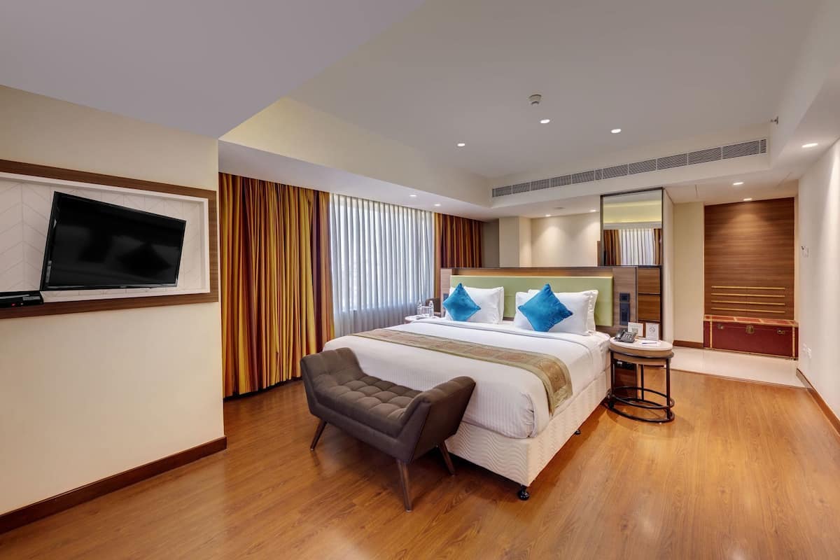 A hotel room with a bed, a desk, a chair, a TV, and a wardrobe.