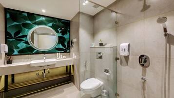 A modern bathroom with a glass-enclosed shower, a white sink, and a large mirror with a leaf-patterned backsplash.