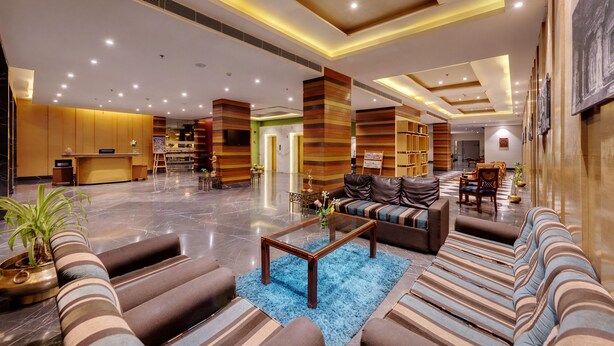 A spacious lobby with a reception desk, seating areas, and a large television. - Amarpreet, Chhatrapati Sambhajinagar - AM Hotel Kollection (Chhatrapati Sambhajinagar)