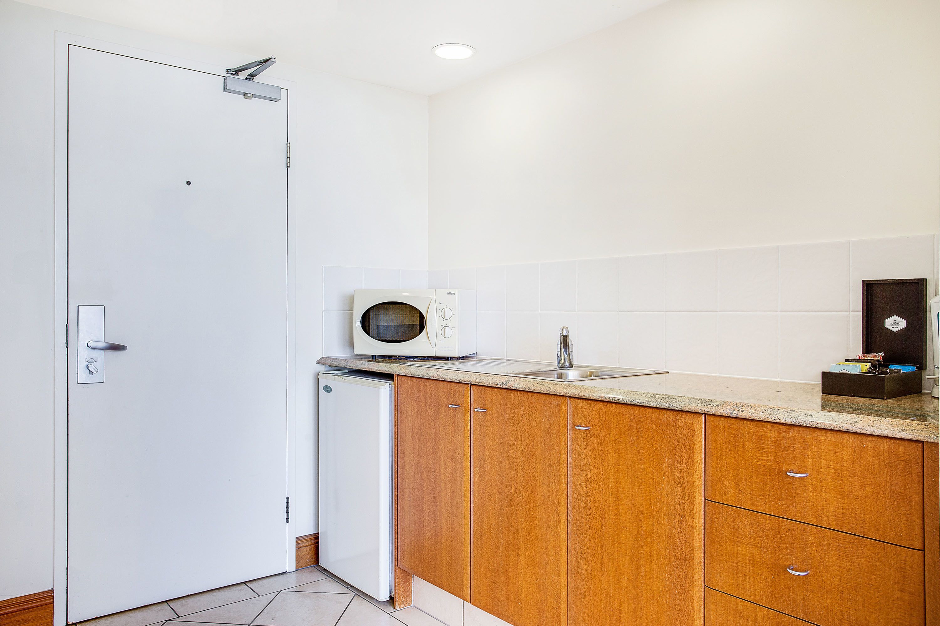 A compact kitchen with a white refrigerator, a microwave, and wooden cabinets.