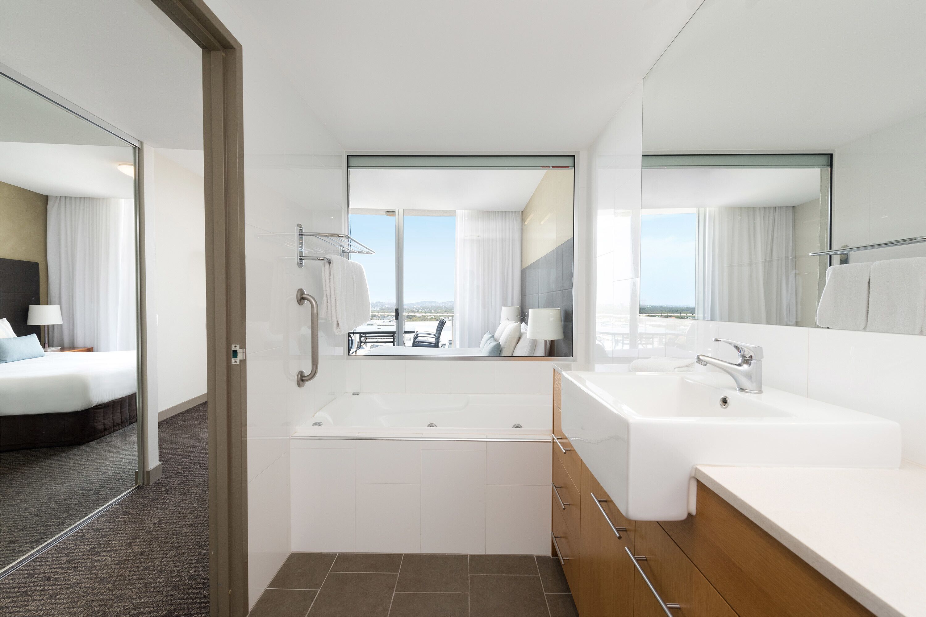 A modern hotel bathroom with a large bathtub, a separate shower area, and a vanity with a sink.