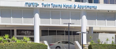 Un hotel moderno con un letrero llamativo, una zona de estacionamiento techada y una escalera que lleva a la entrada.
