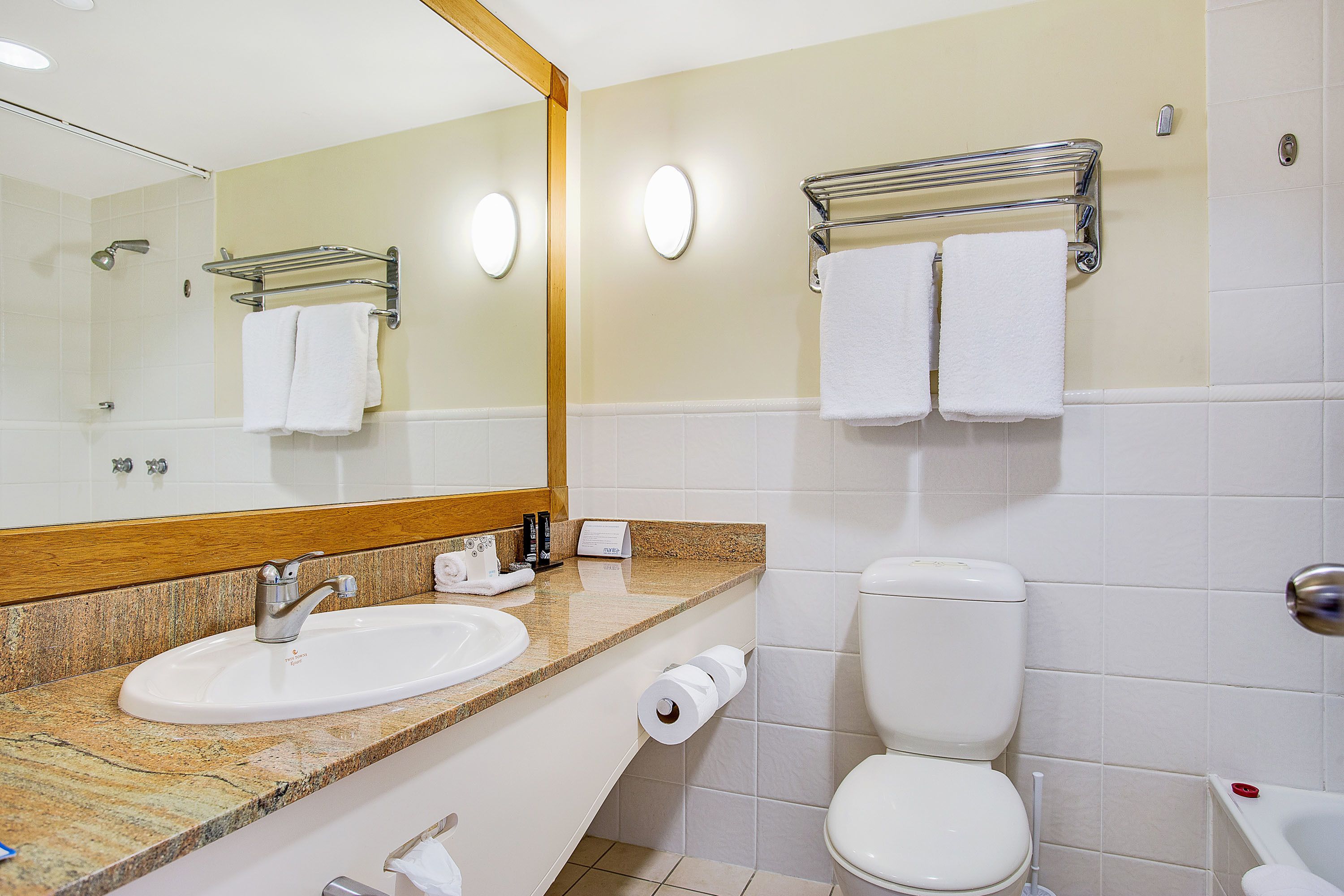 A bathroom with a sink, toilet, and a mirror.
