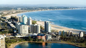 A coastal cityscape with high-rise buildings, a beach, and a marina.