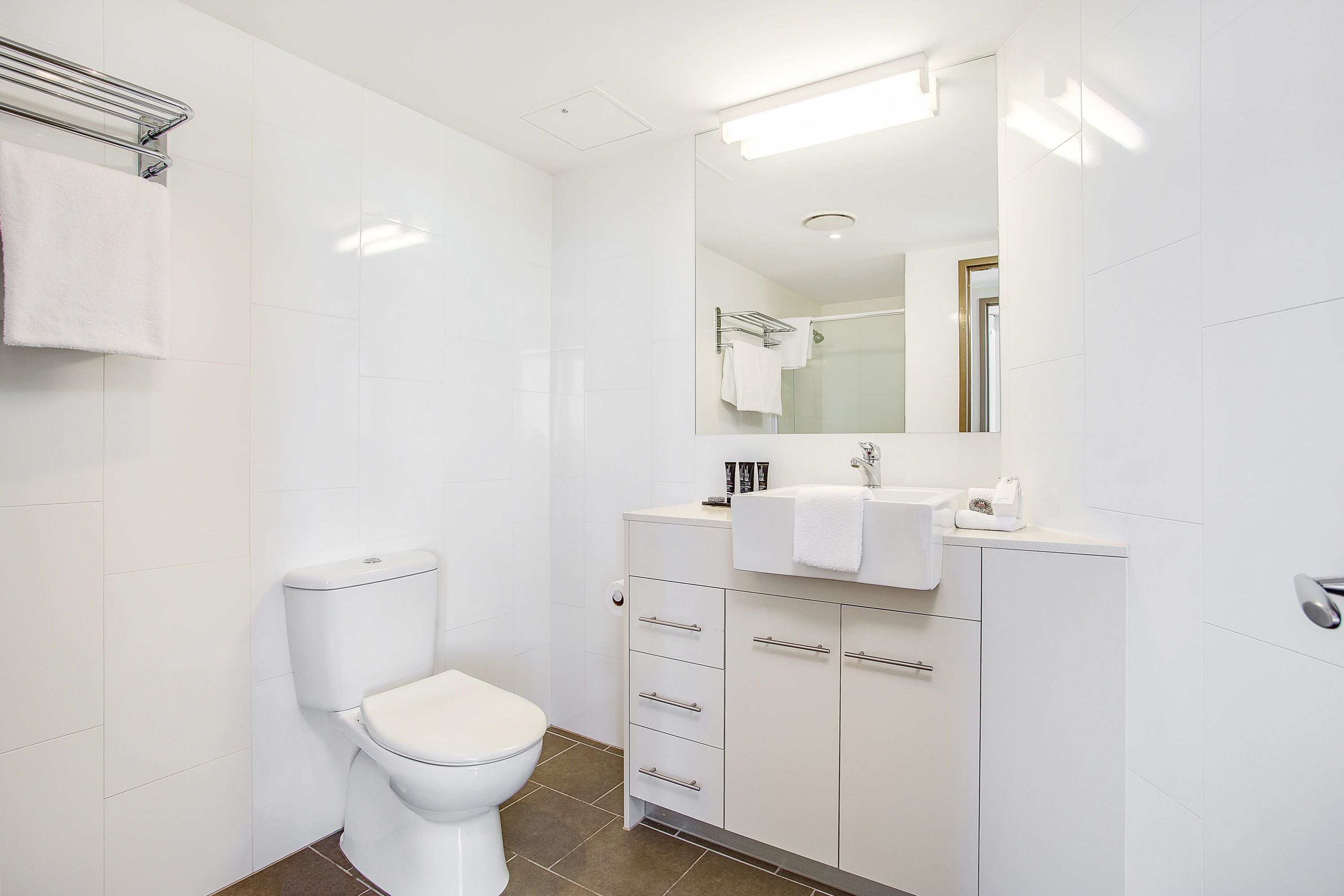 A modern bathroom with a toilet, a sink, and a mirror.