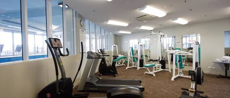 Un gimnasio con cintas de correr, elípticas y equipo de pesas.