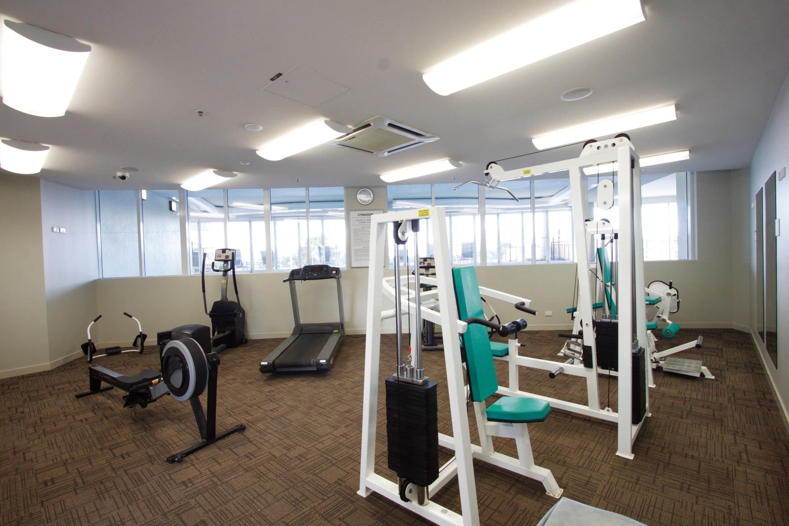 A gym with exercise equipment, a treadmill, and large windows.
