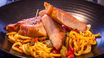 A plate of food with noodles, vegetables, and slices of meat.