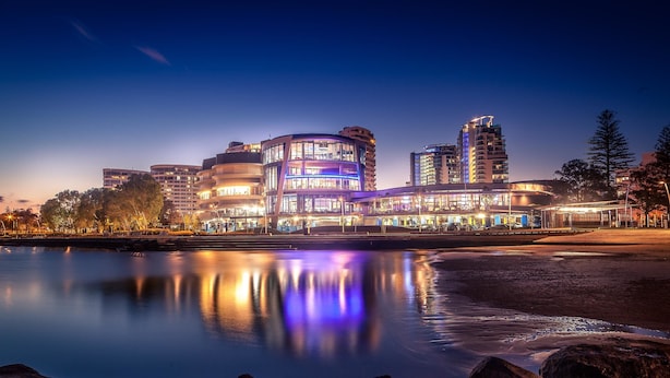 A waterfront hotel with a modern design, featuring a curved building with multiple balconies and a reflection in the water. - Mantra Twin Towns (Tweed Heads)