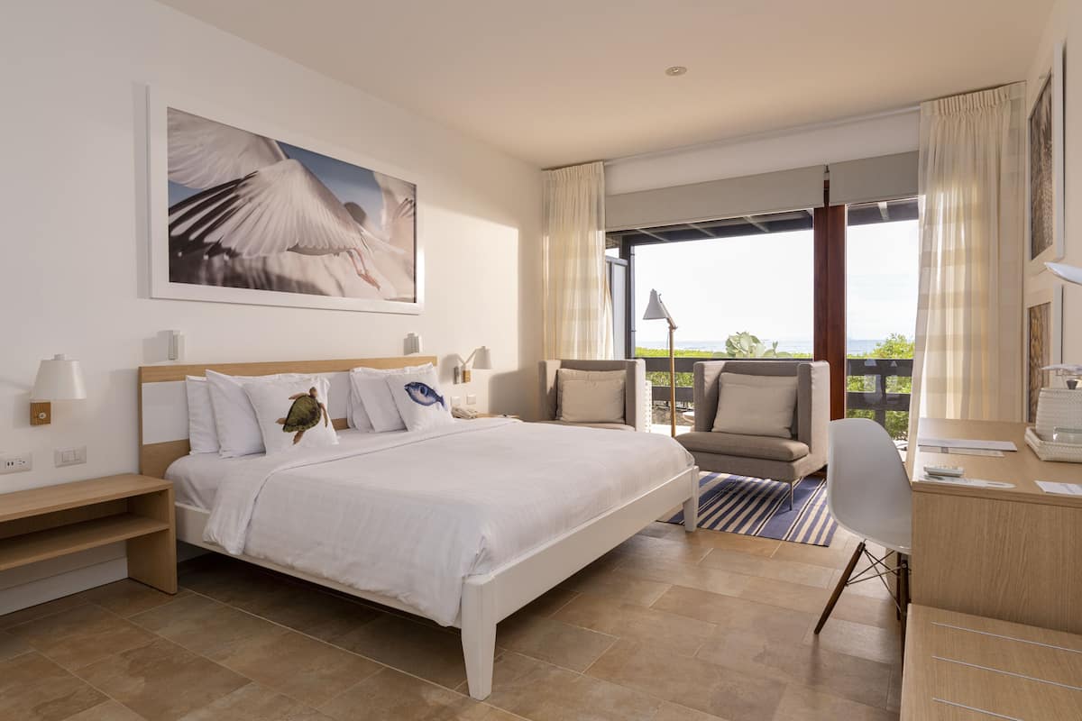 Habitación de hotel con cama, escritorio, silla y vistas al exterior.